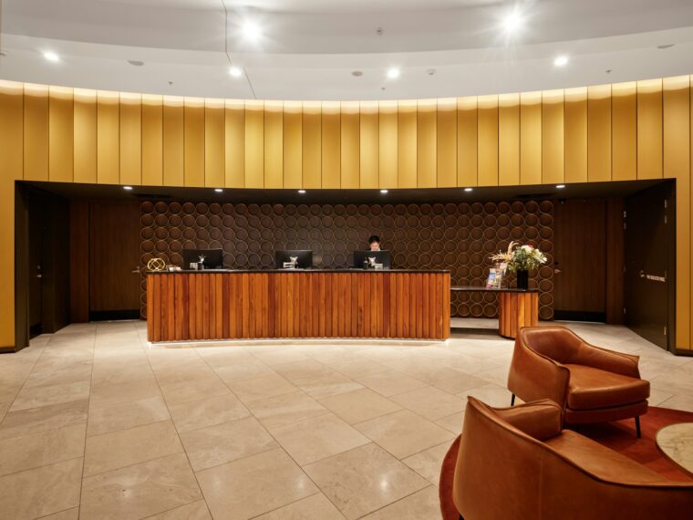 Hotel reception desk with modern wooden furniture and seating.