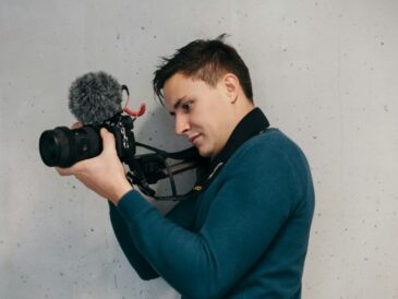 man in blue sweater using DSLR camera