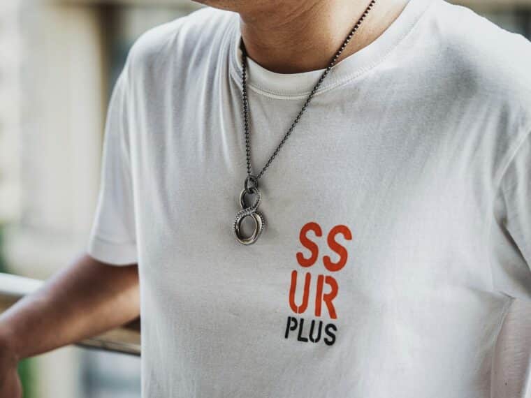 a man wearing a white tshirt and a necklace
