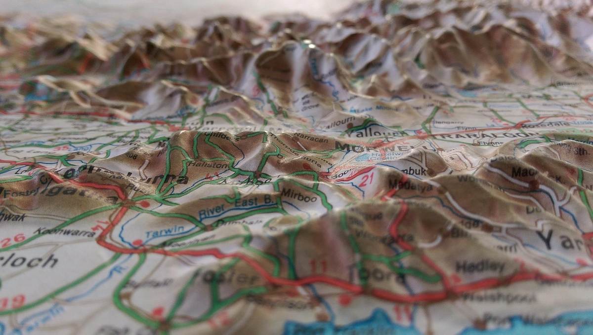 Carte topographique pliée montrant des reliefs montagneux et des routes colorées Carte topographique pliée montrant des reliefs montagneux et des routes colorées