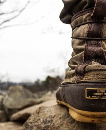 Botte de marche sur rocher, forêt enneigée, ciel gris