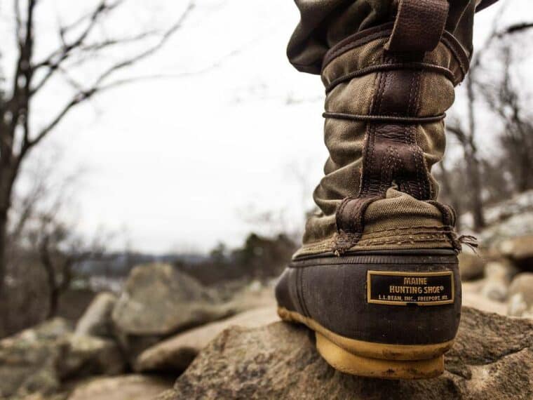 Botte de marche sur rocher, forêt enneigée, ciel gris