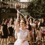 bride throwing flower bouquet on women during daytime