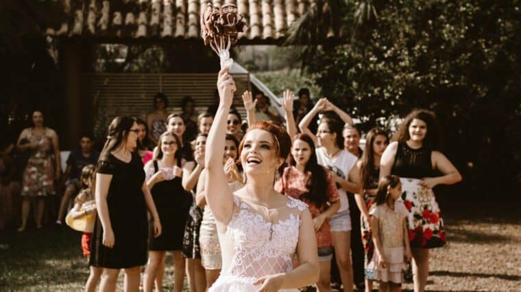 bride throwing flower bouquet on women during daytime
