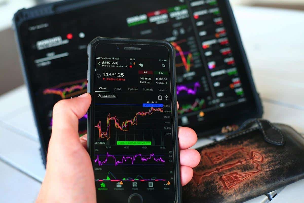 Graphiques financiers sur smartphone et tablette, portefeuille en cuir sur une table