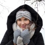 Une femme chaleureusement vêtue souriante sous la neige