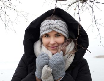 Une femme chaleureusement vêtue souriante sous la neige