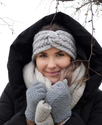 Une femme chaleureusement vêtue souriante sous la neige
