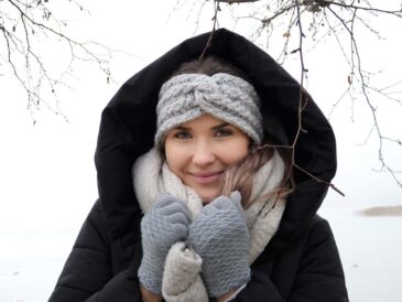 Une femme chaleureusement vêtue souriante sous la neige