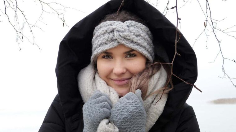 Une femme chaleureusement vêtue souriante sous la neige