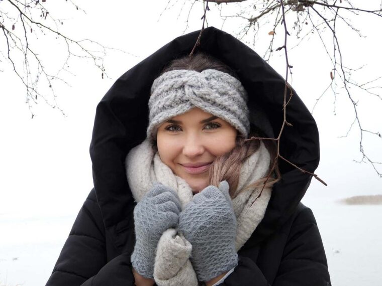 Une femme chaleureusement vêtue souriante sous la neige