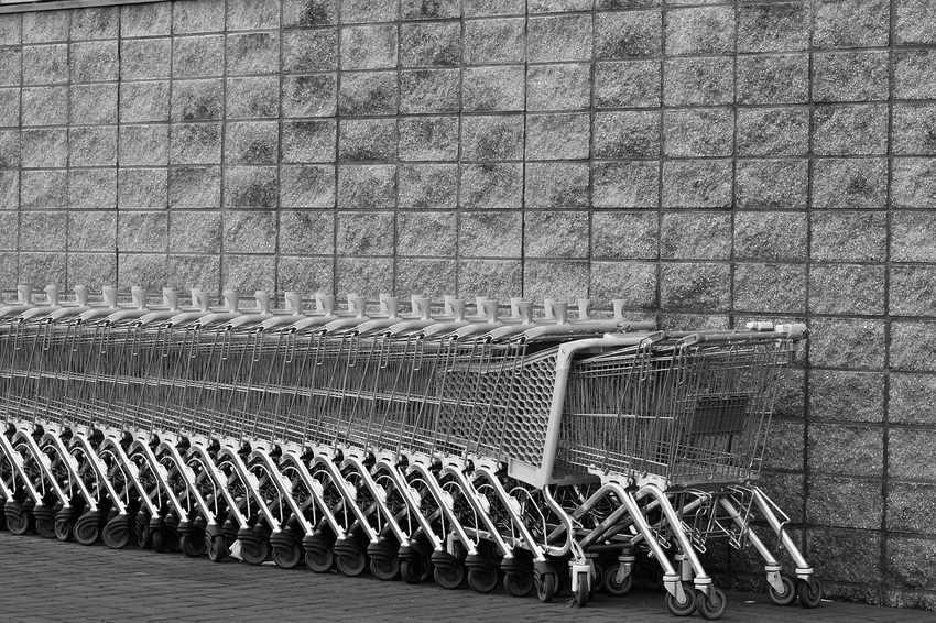 Rangée de chariots de supermarché métalliques alignés le long d'un mur en béton