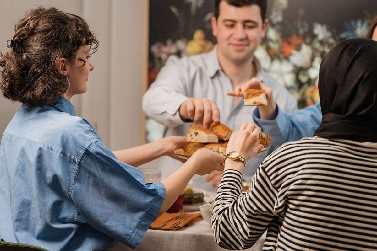 Personnes partageant un repas, une assiette de pain et une boisson sur la table